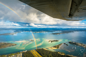 A rainbow over an airport located near the coast.